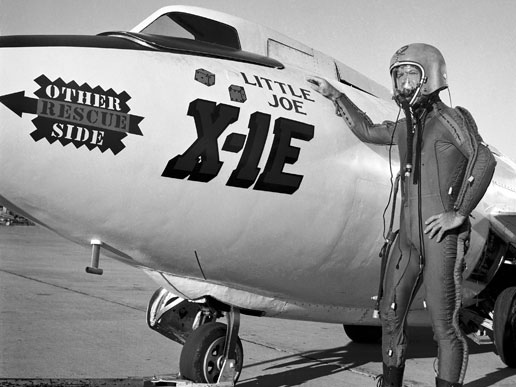 NASA test pilot Joseph Walker in a pressure suit stands beside the X-1E.