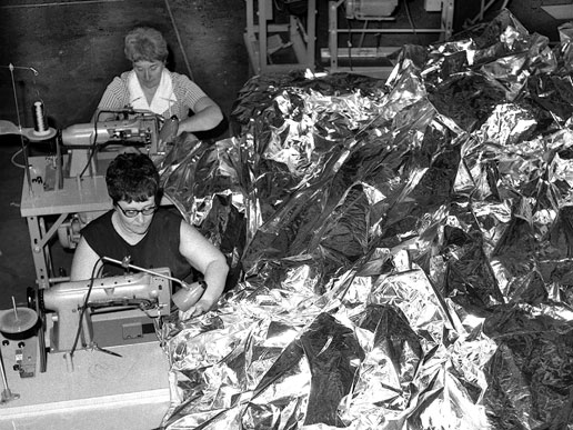 Two seamstresses stitch together a sun-shade for the Skylab Orbital Workshop.