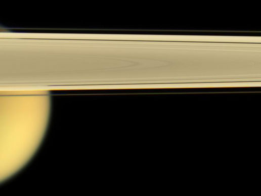 Saturn's largest moon, Titan, peaks out from under the planet's rings of ice.